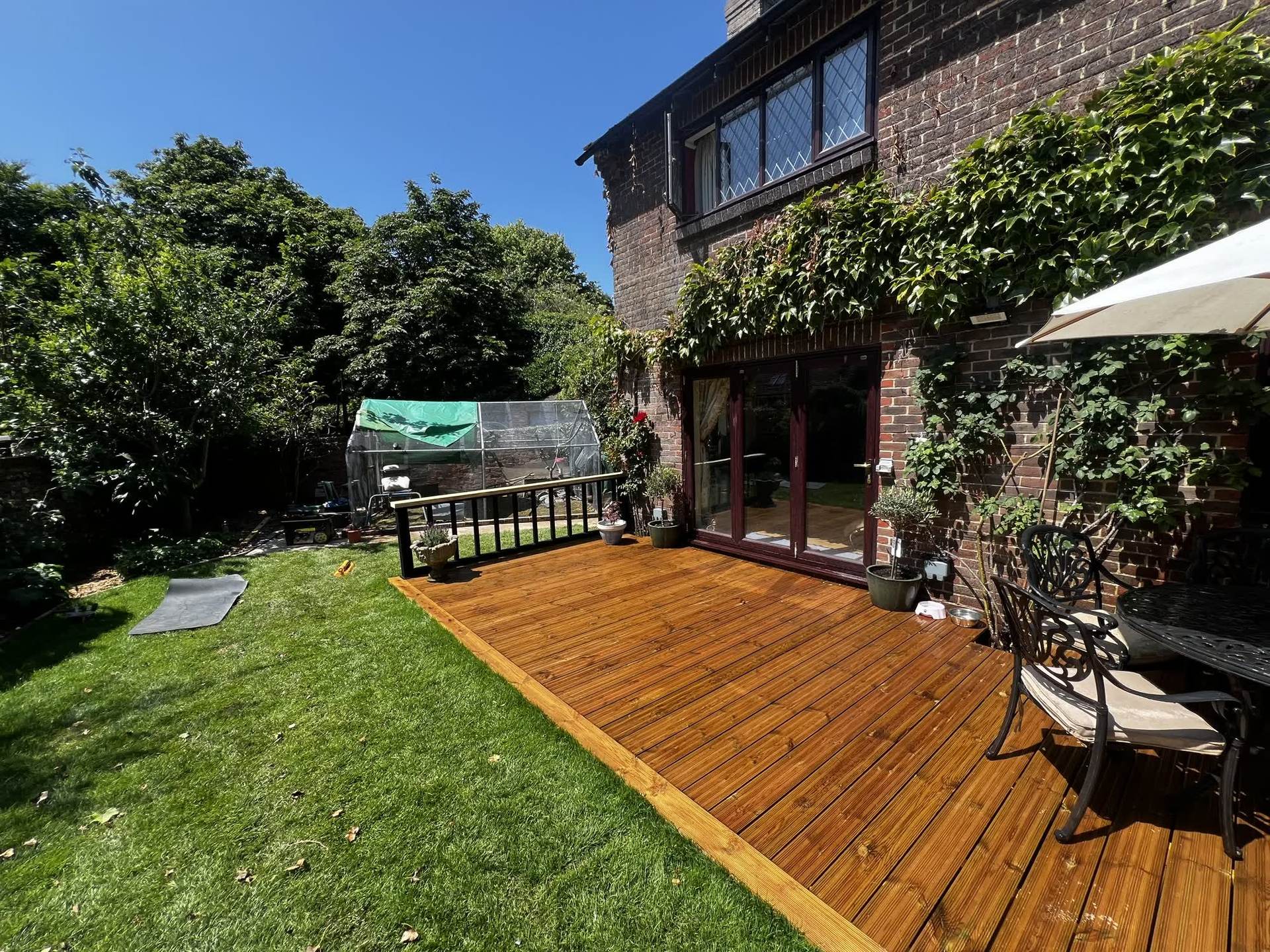 The newly built timber deck and freshly laid lawn, with outdoor furniture back in place before the grey stain was applied