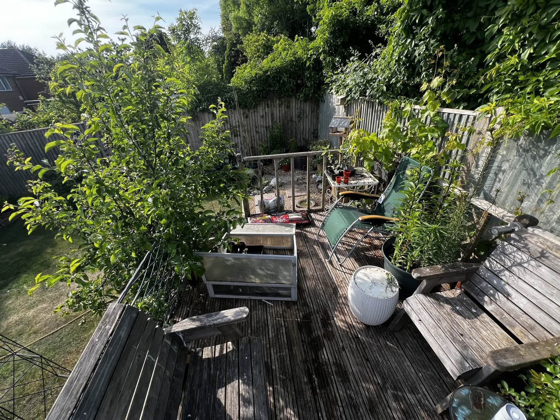 The previous deck crowded with garden furniture, planters and a stored greenhouse frame before the rebuild