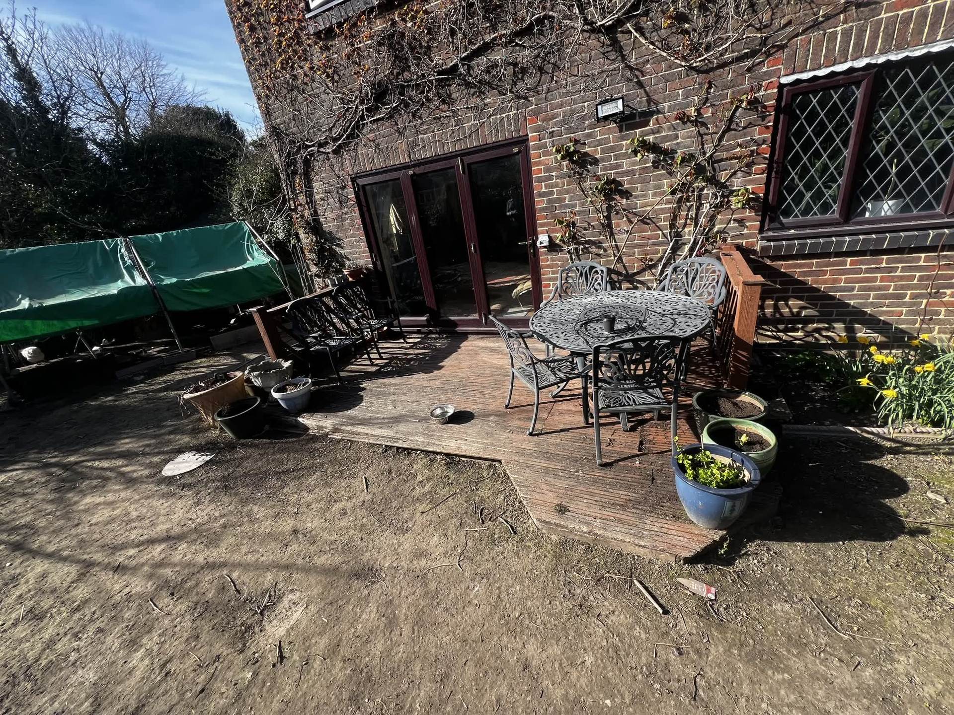 The original deck and outdoor furniture surrounded by bare, unfinished ground before the renovation began