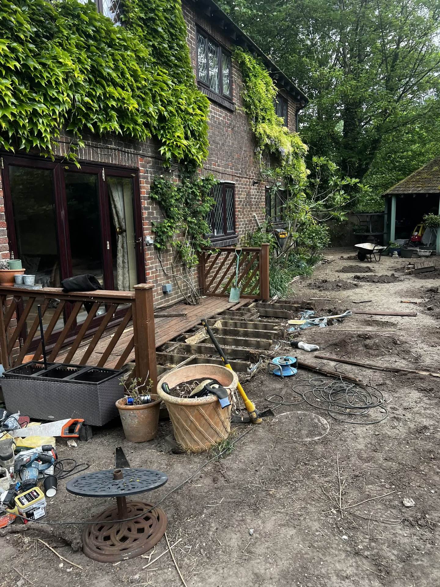 The old deck partially demolished, with the timber joists exposed and the surrounding ground dug out