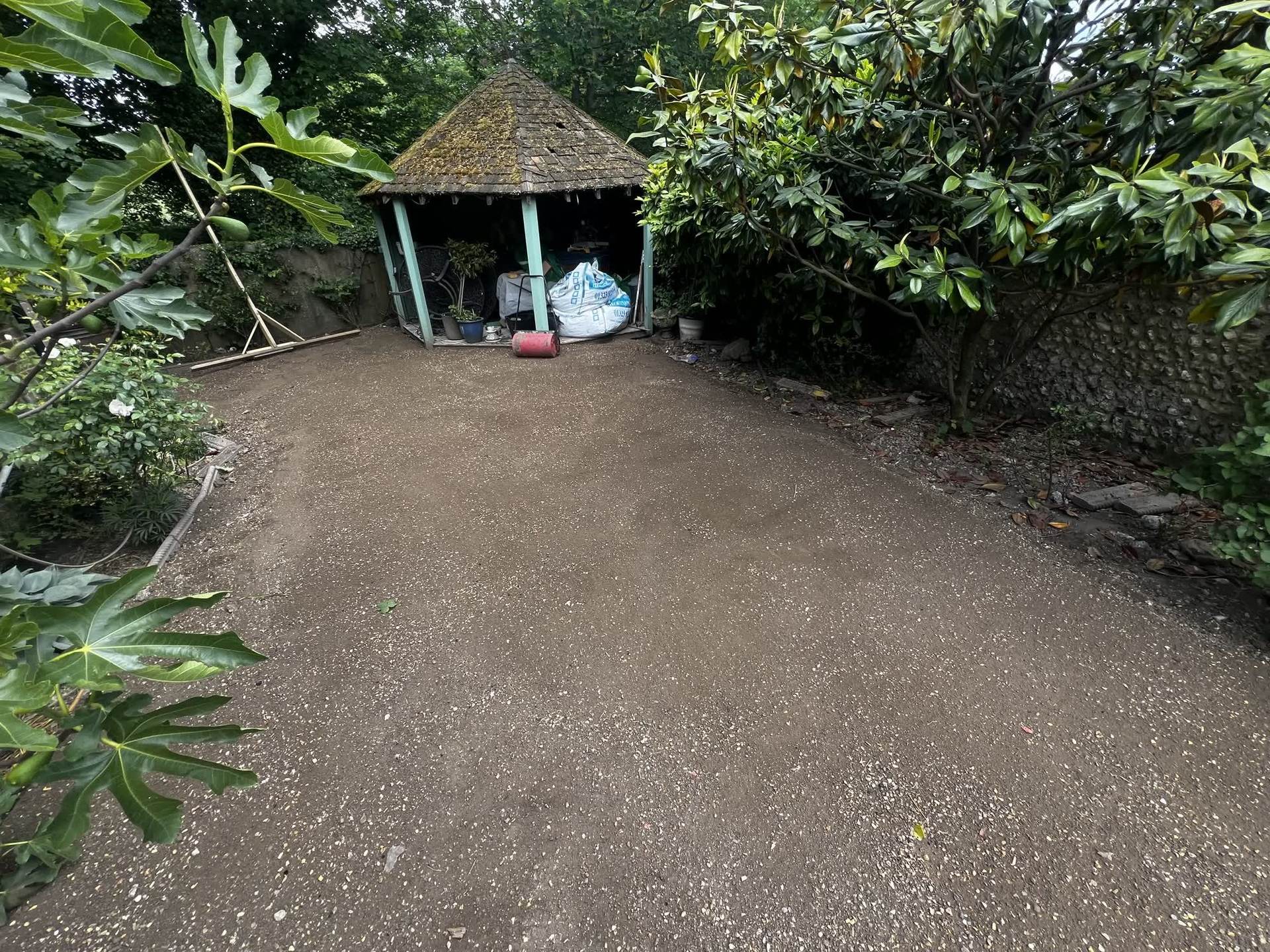 The cleared, compacted ground next to the garden gazebo, prepared and ready for new turf