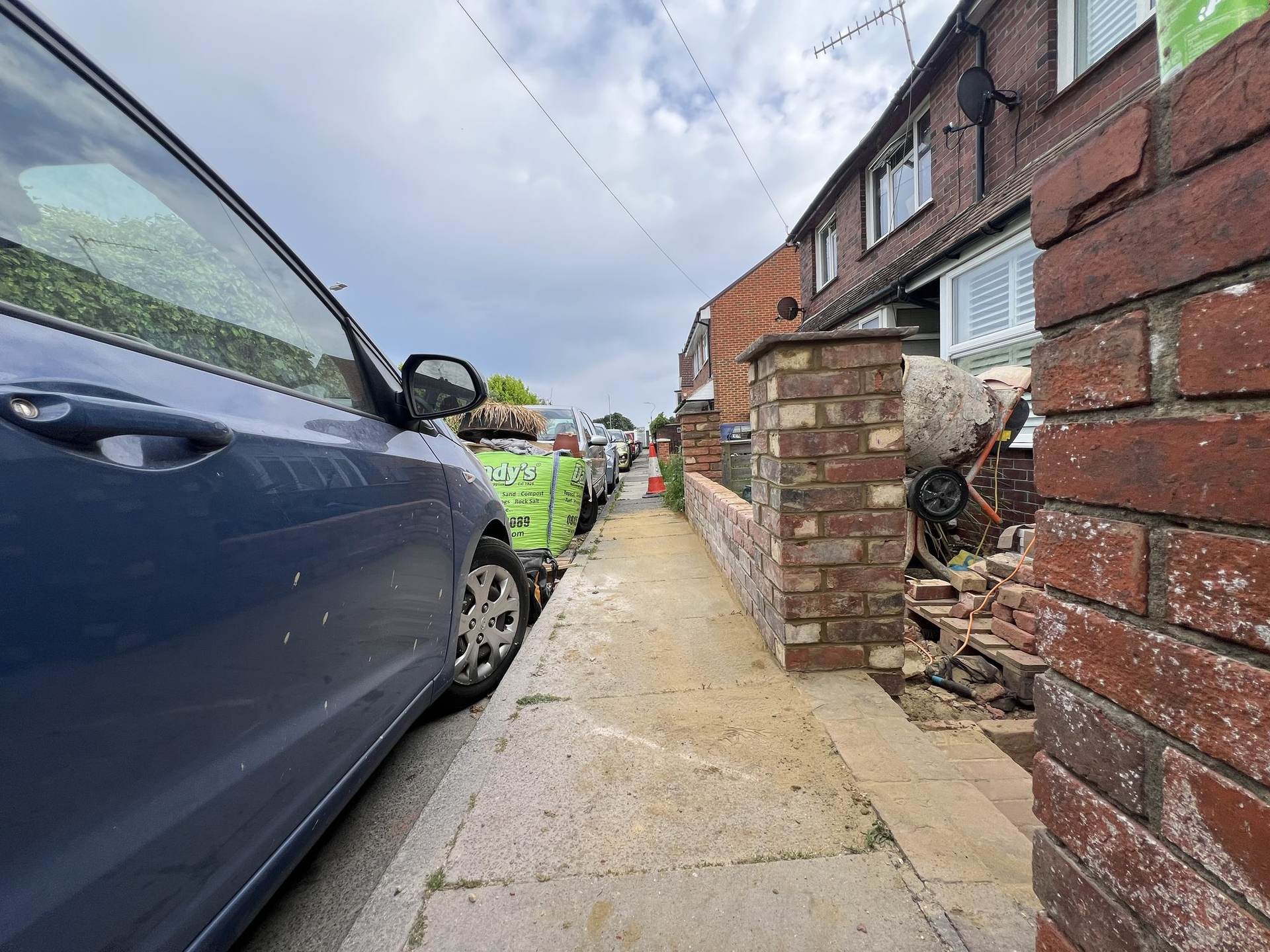 The new brick boundary wall under construction, with cement mixer and materials on site
